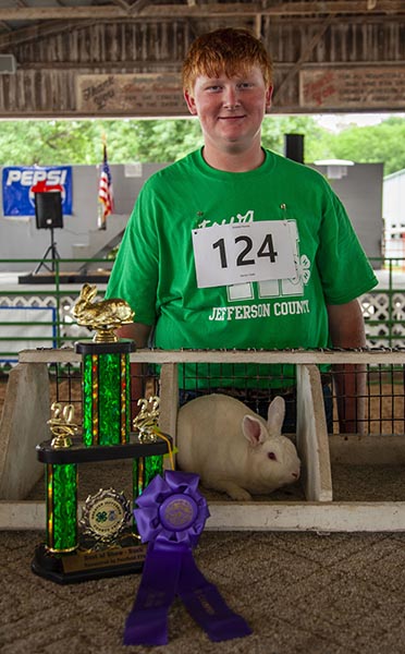 A man standing next to a rabbit in an enclosure.