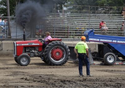 A man standing next to a tractor pulling a trailer.